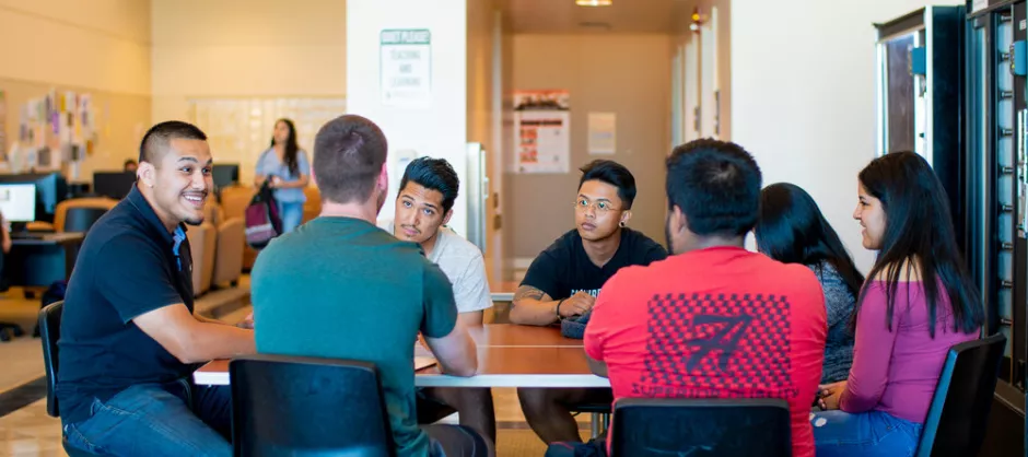 a group of students sitting around a table intently looking at each other