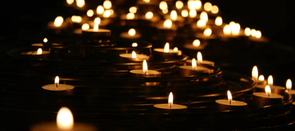 A group of lit candles on the ground in an otherwise dark room.