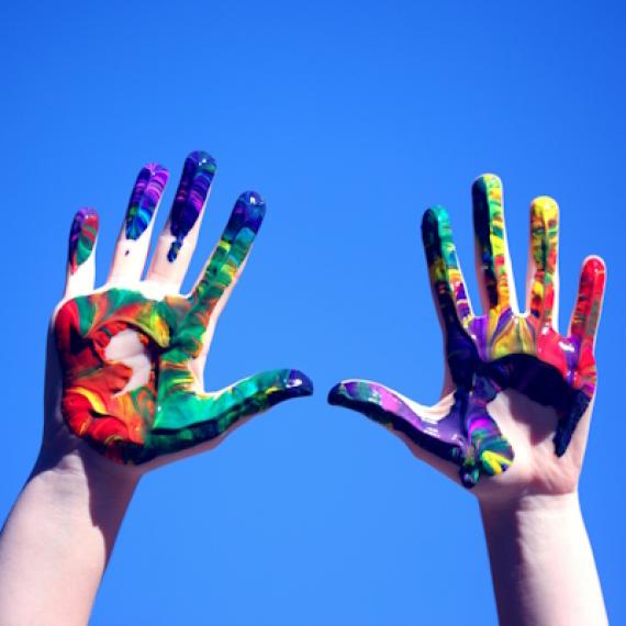 Hands with paint on them with blue sky in the background