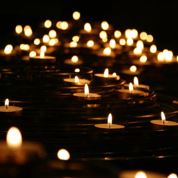 A group of lit candles on the ground in an otherwise dark room.