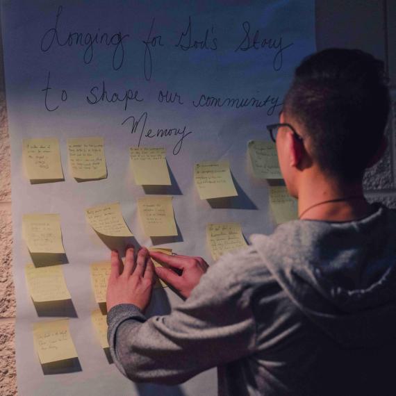 a photo of a young man putting sticky notes onto a wall